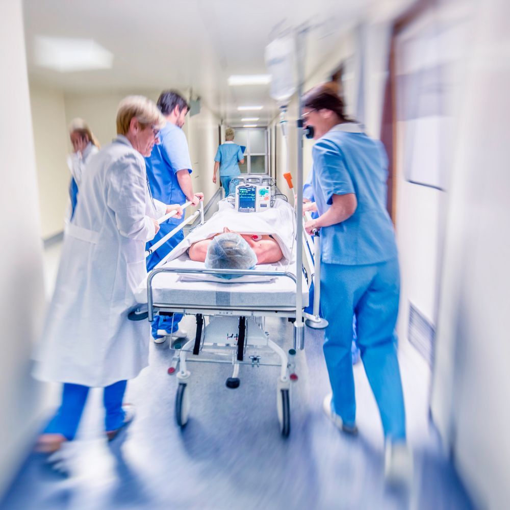 Medical staff transporting a patient on a hospital stretcher in an advanced trauma care unit.