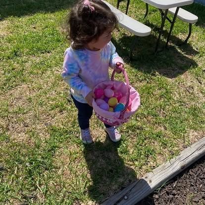 A little girl is holding a basket full of easter eggs.