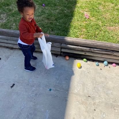 A little boy is playing with easter eggs on the ground.