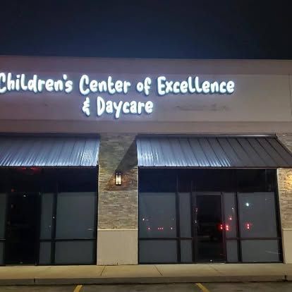 The children 's center of excellence & daycare building is lit up at night.