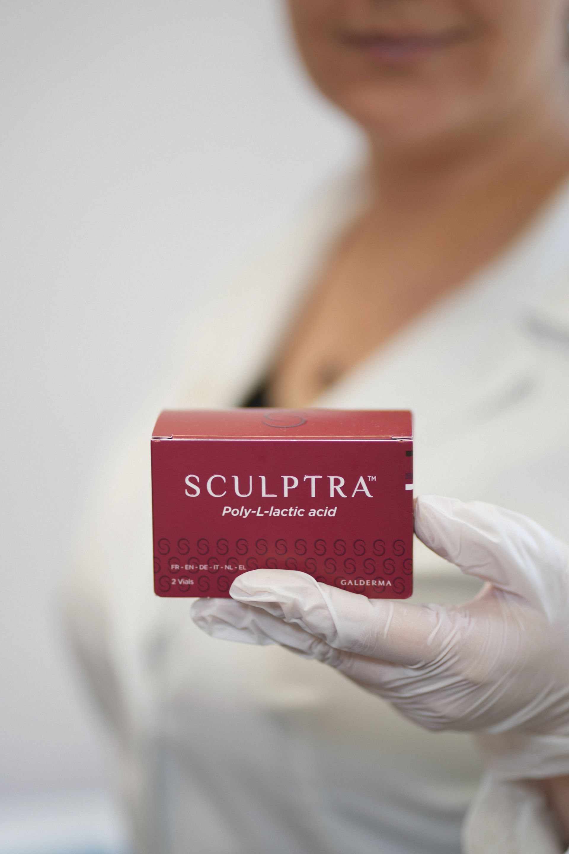 A woman is holding a box of sculptra in her hand.