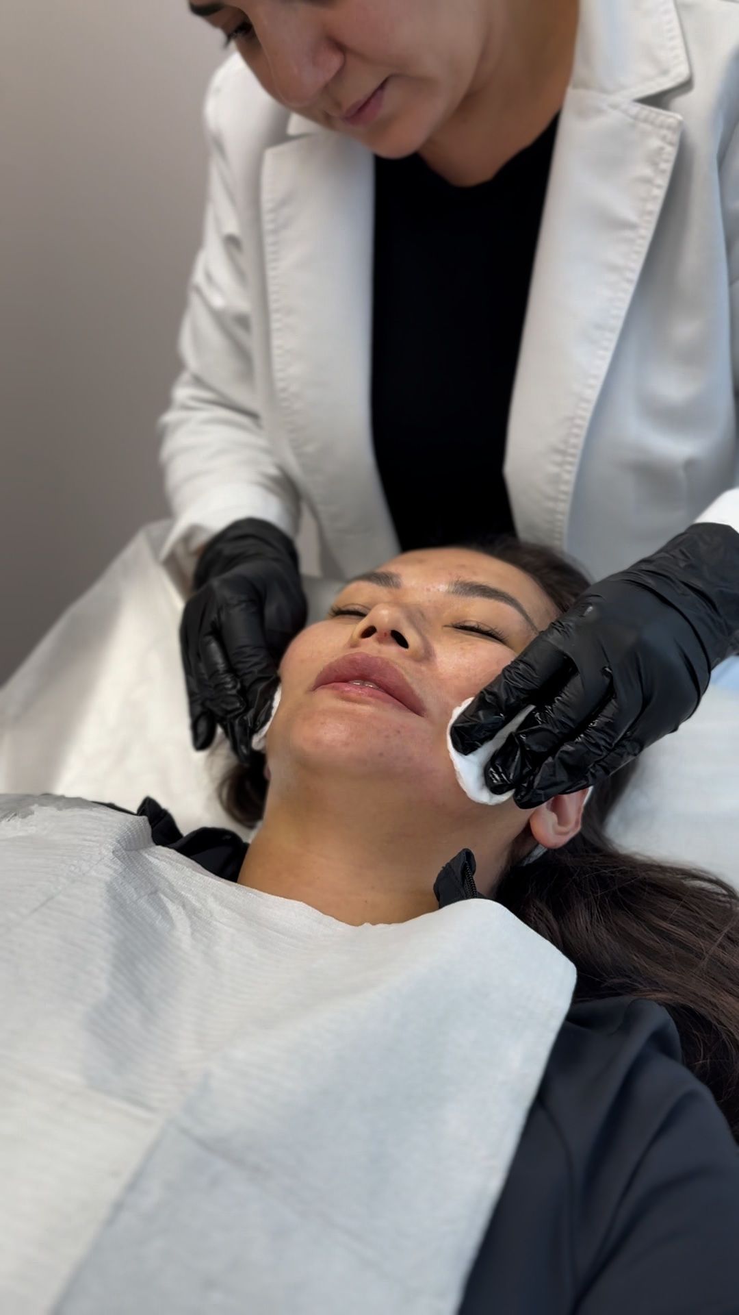 A woman is getting her face cleaned by a doctor.