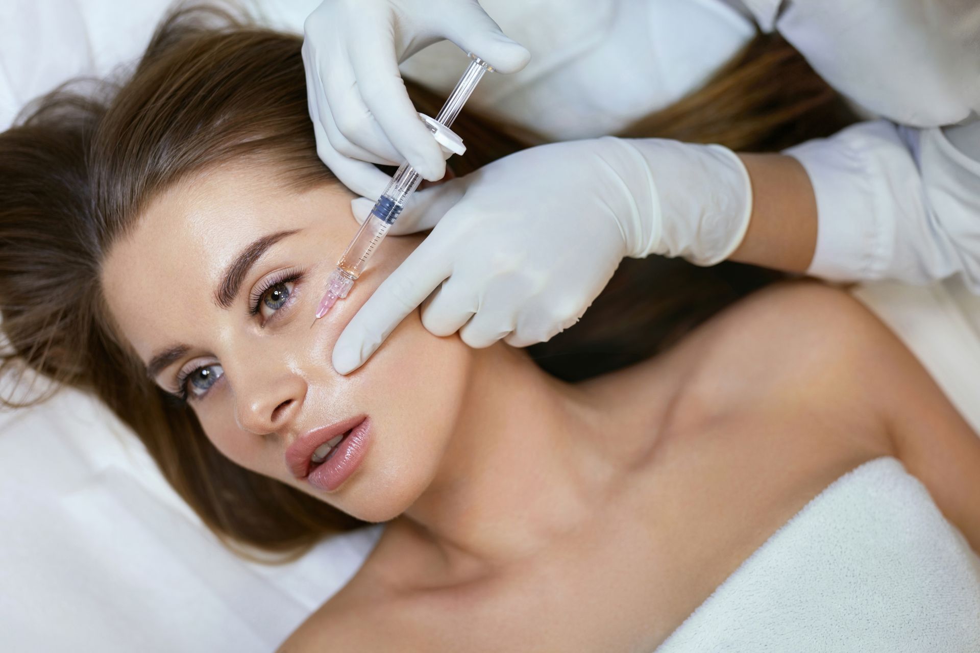 A woman is getting a injection in her face.