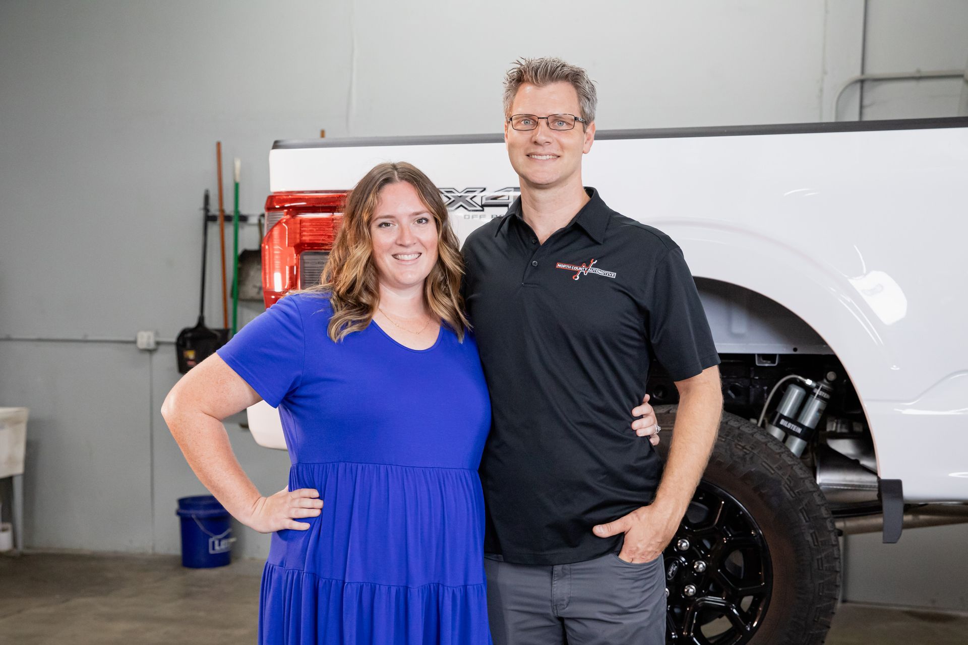 A man and a woman are posing for a picture in front of a white truck.