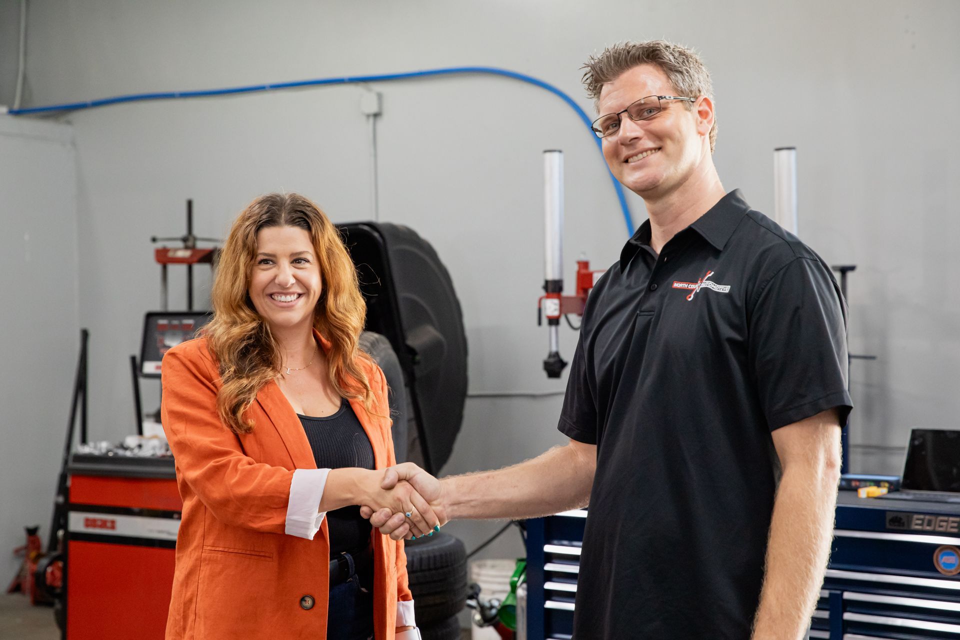 A man and a woman are shaking hands in a garage.