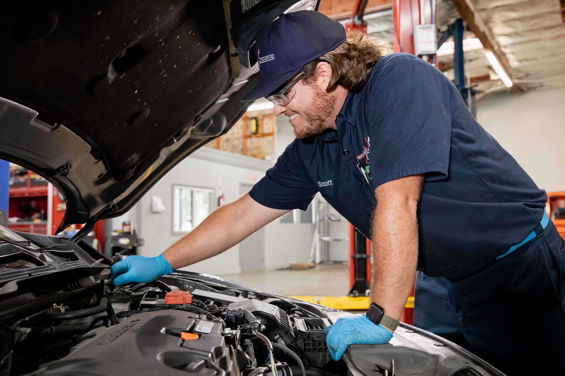 A man is working on the engine of a car in a garage.