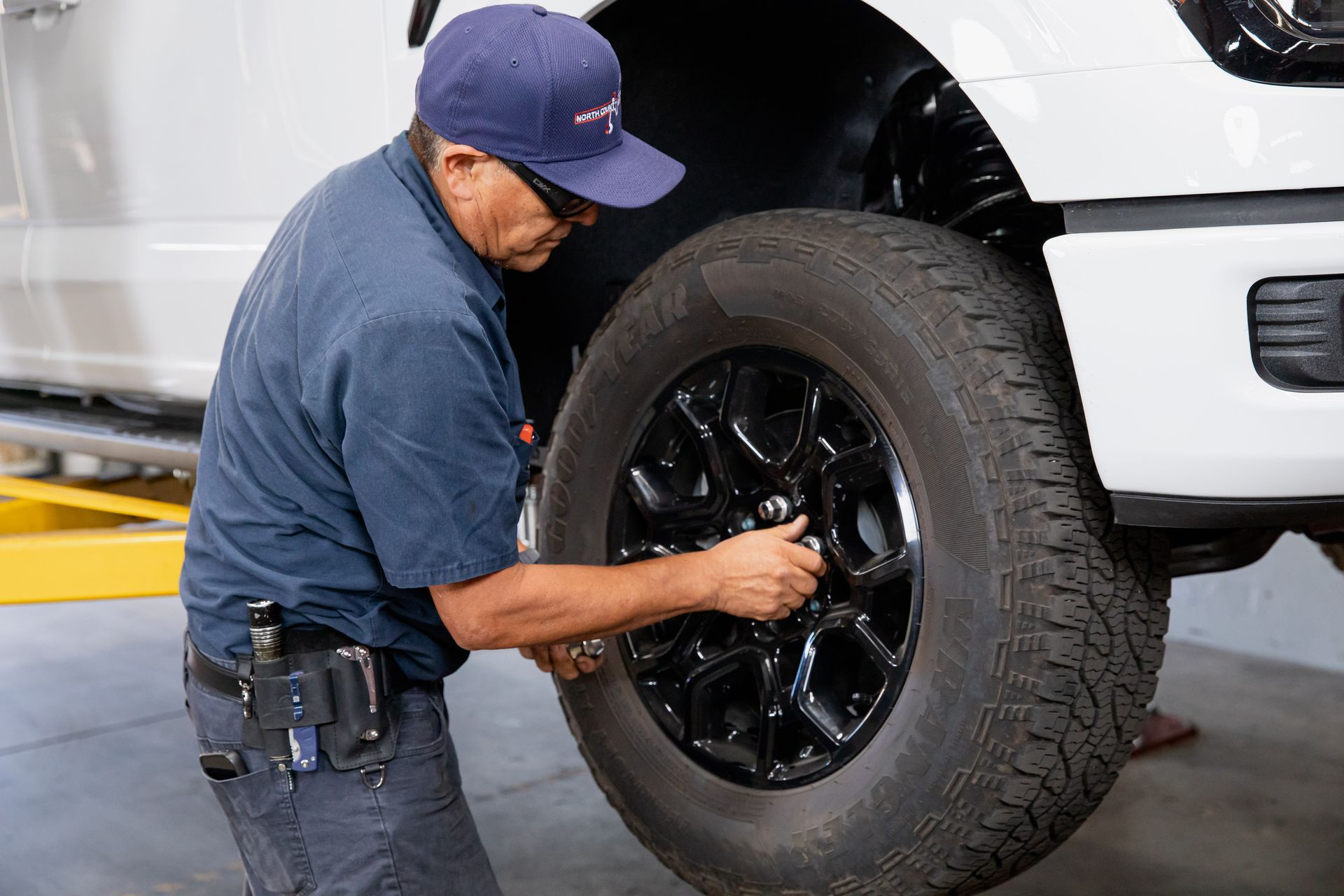 A man is working on a tire on a white truck.