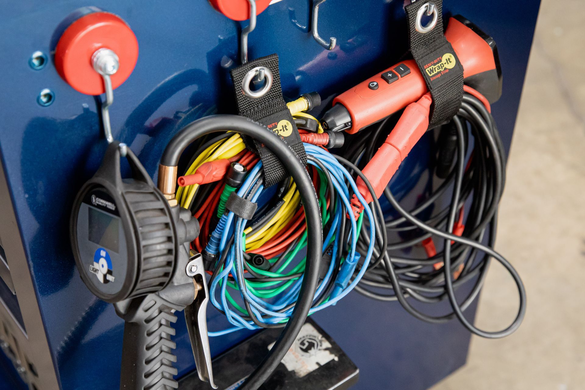 A bunch of wires are hanging from hooks on a wall.