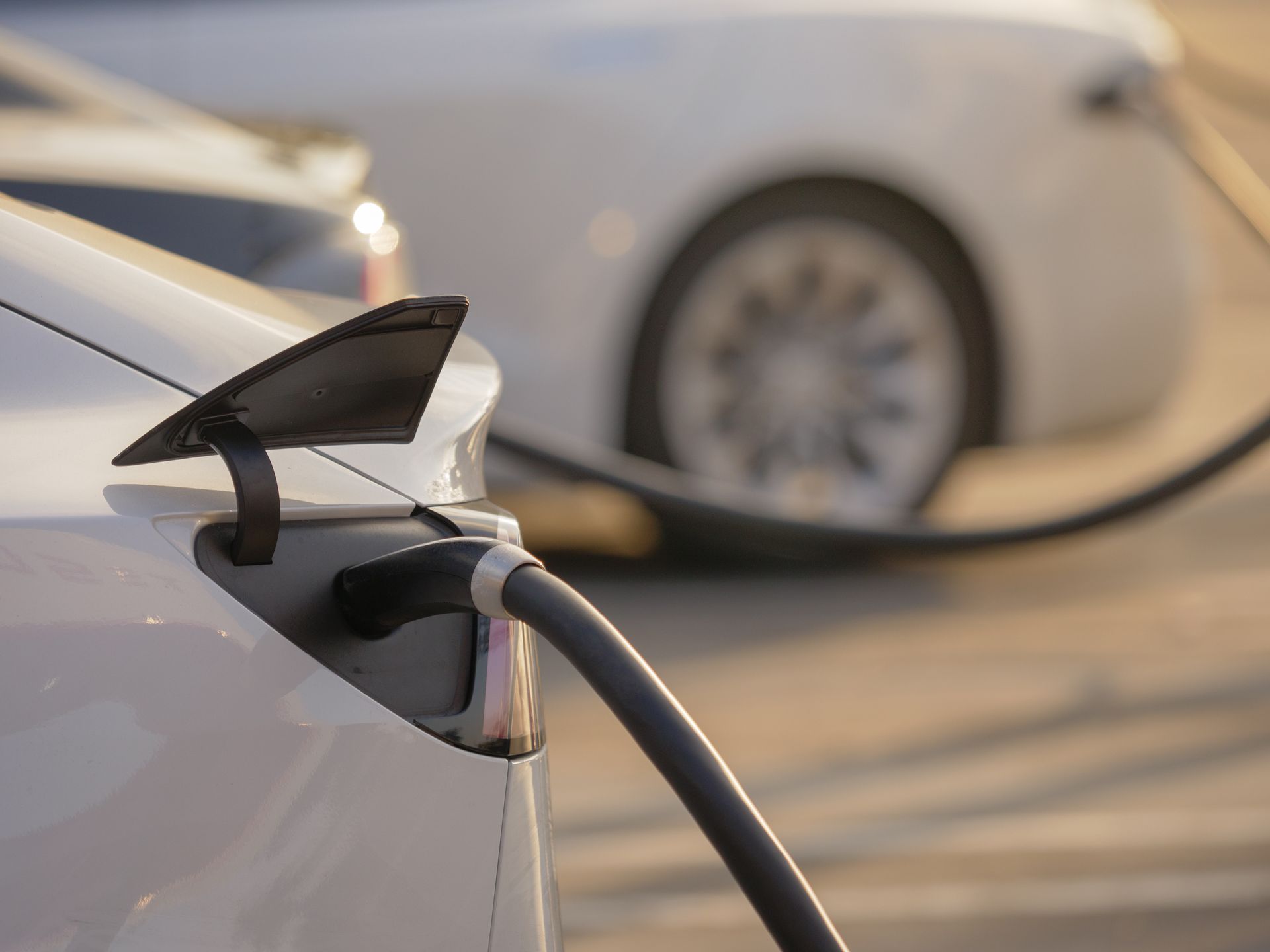A white electric car is being charged at a charging station.