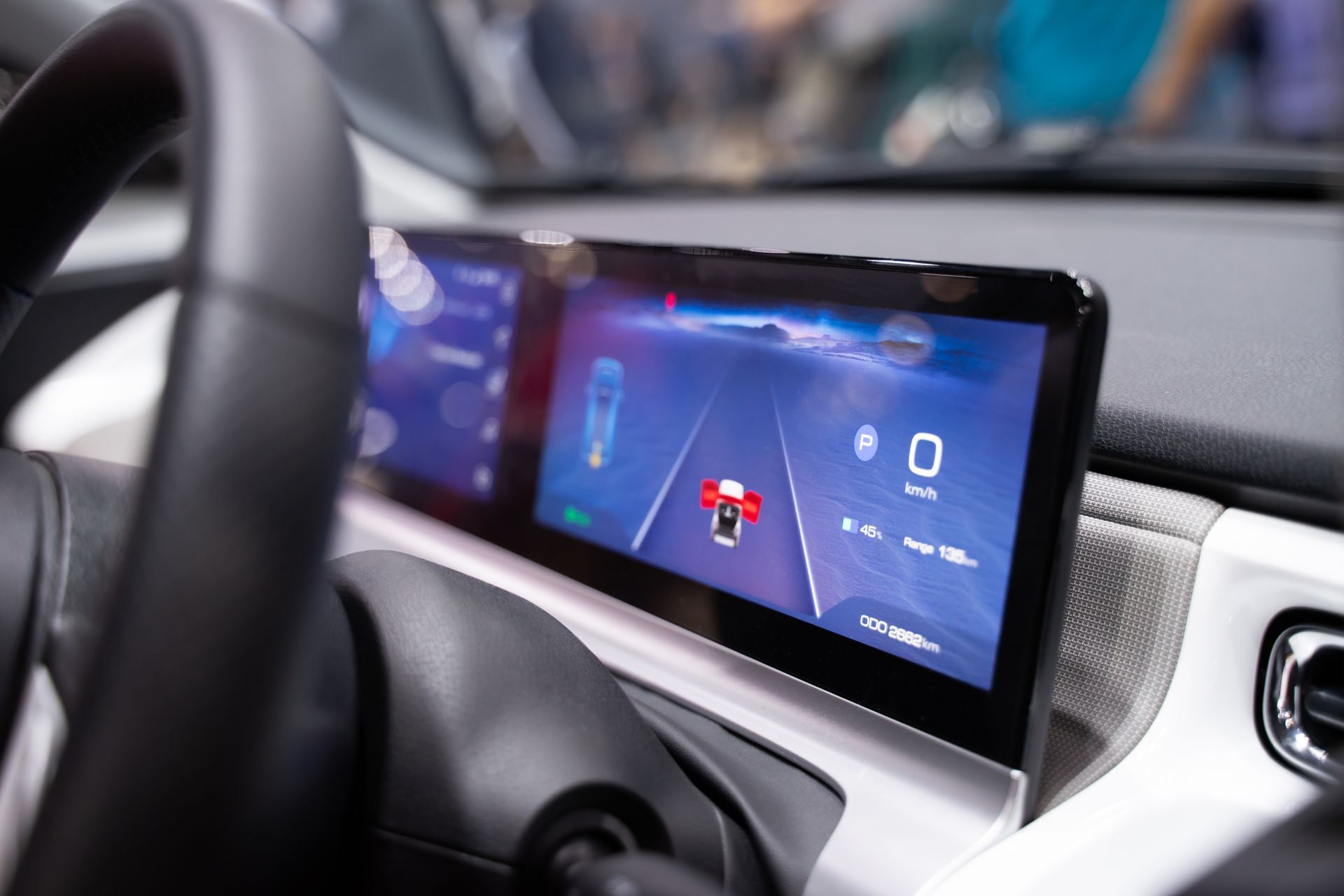 A close up of a car dashboard with a steering wheel and a screen.