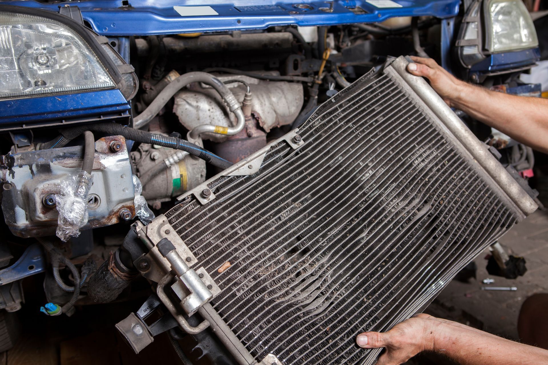 A person is holding a radiator in front of a car.