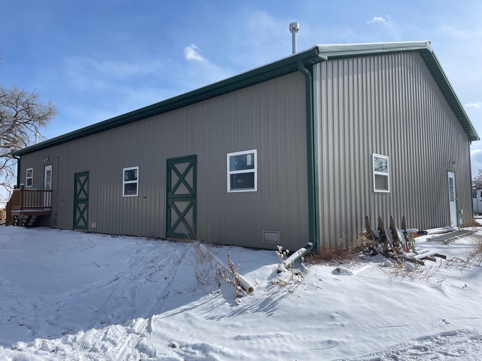 A large, new metal barn with white and dark brown siding, a covered porch, and a concrete slab.
