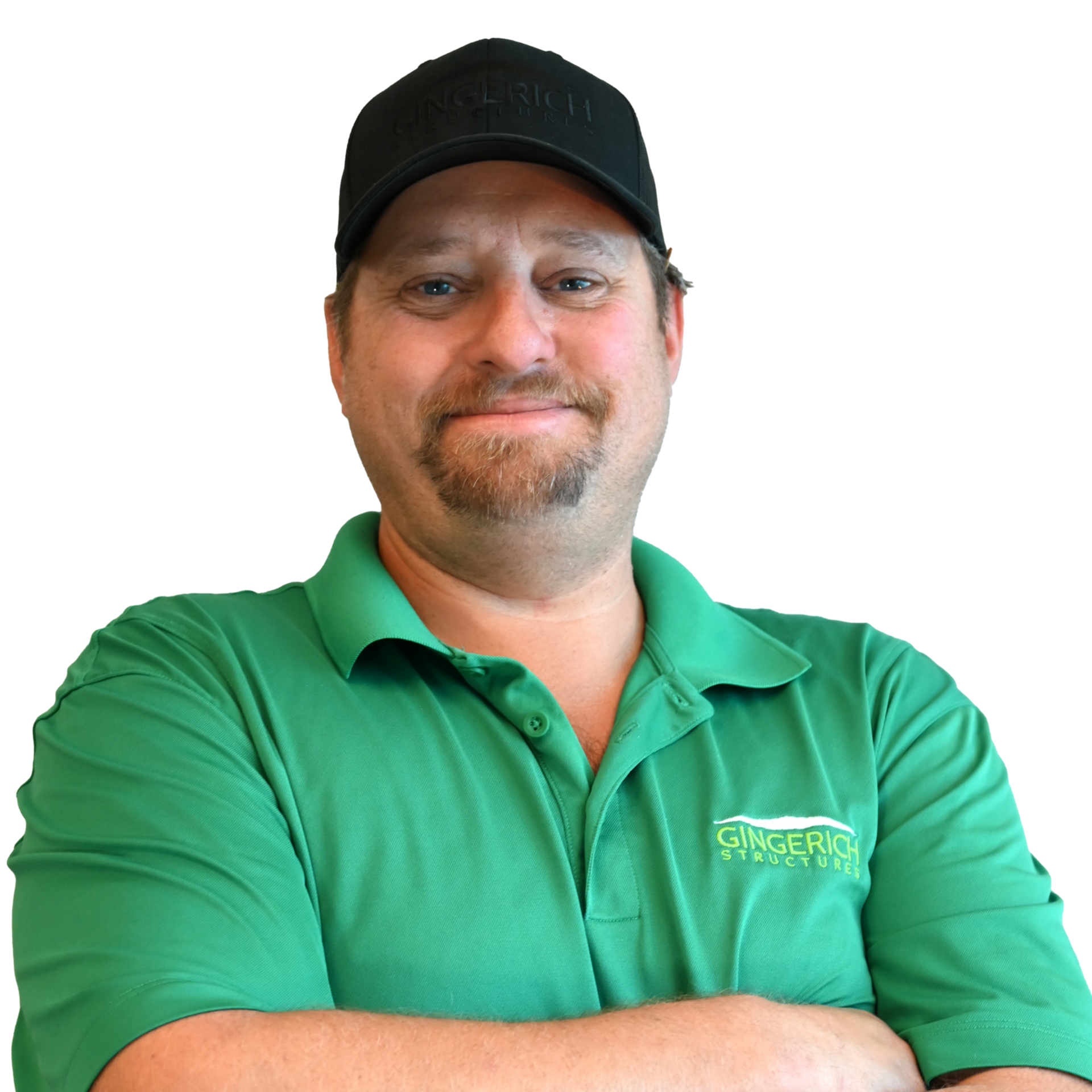 Man in green polo shirt and black cap smiling with arms crossed.