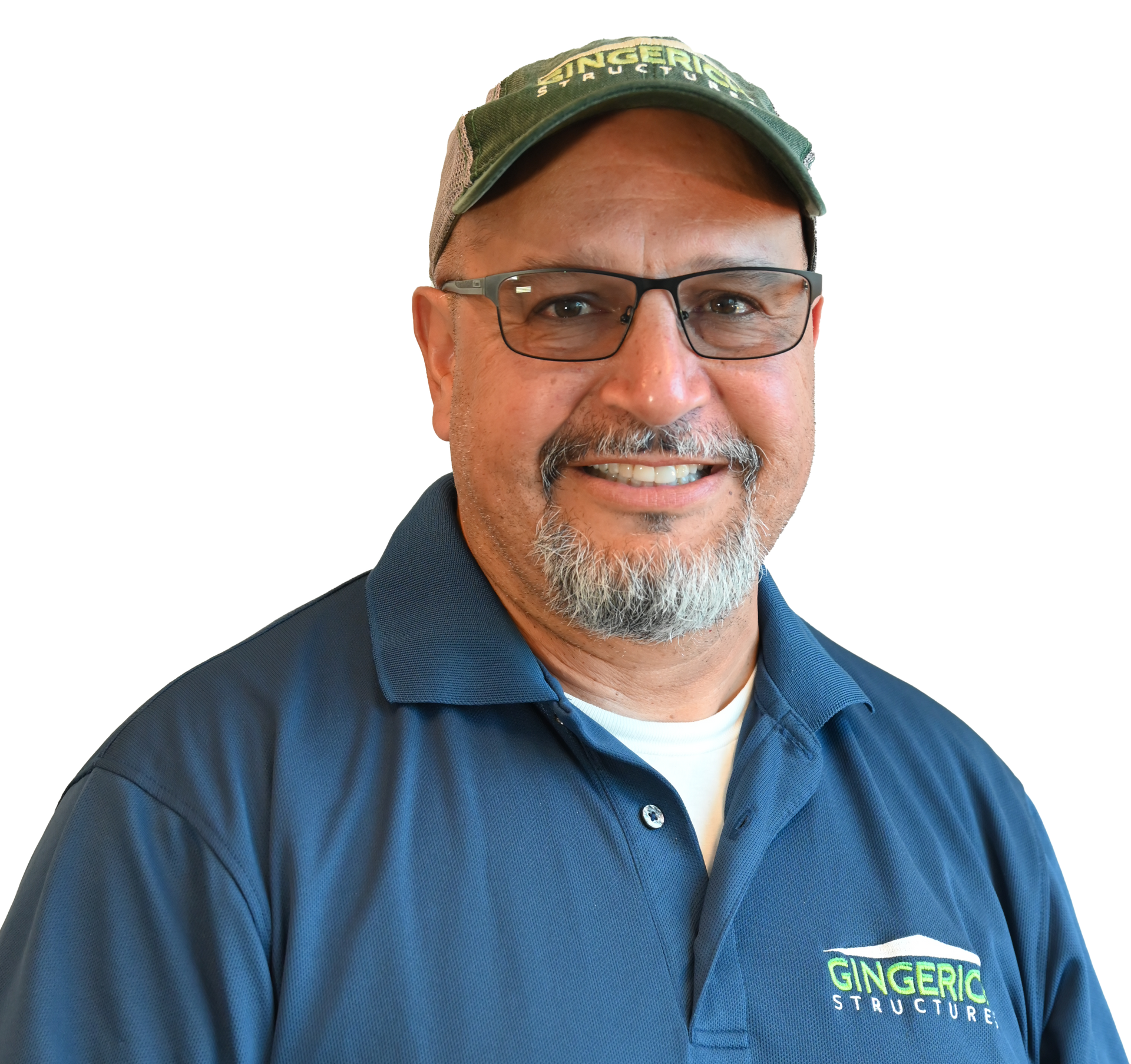 Man wearing glasses and a green cap, smiling in front of a white backdrop, with a blue shirt.