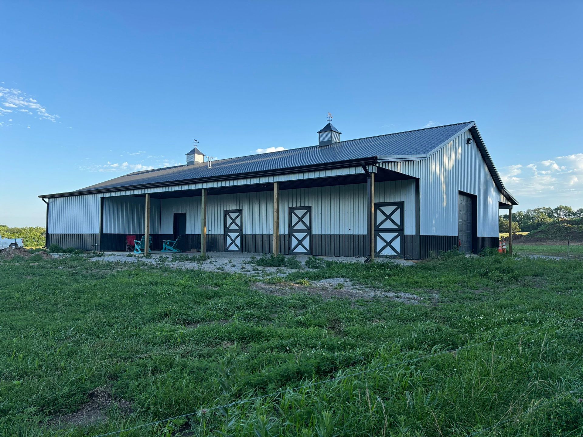White post-frame barn with cupola and covered porch — custom Gingerich Structures building
