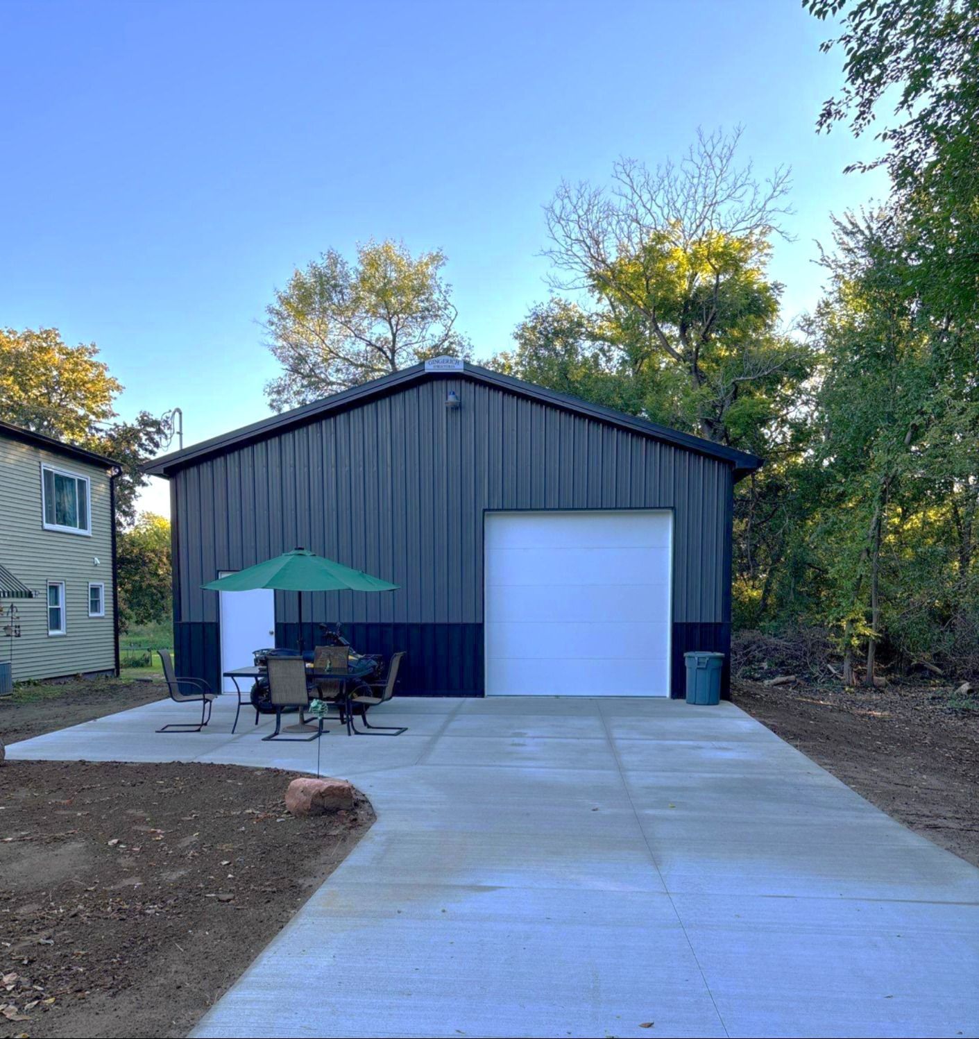 White farmhouse with covered porch, two-story, and attached garage on a sunny day.