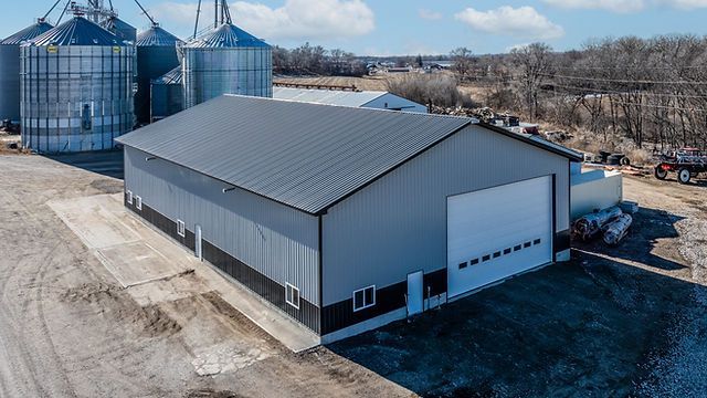 Tan and gray barn with a porch under a blue sky.