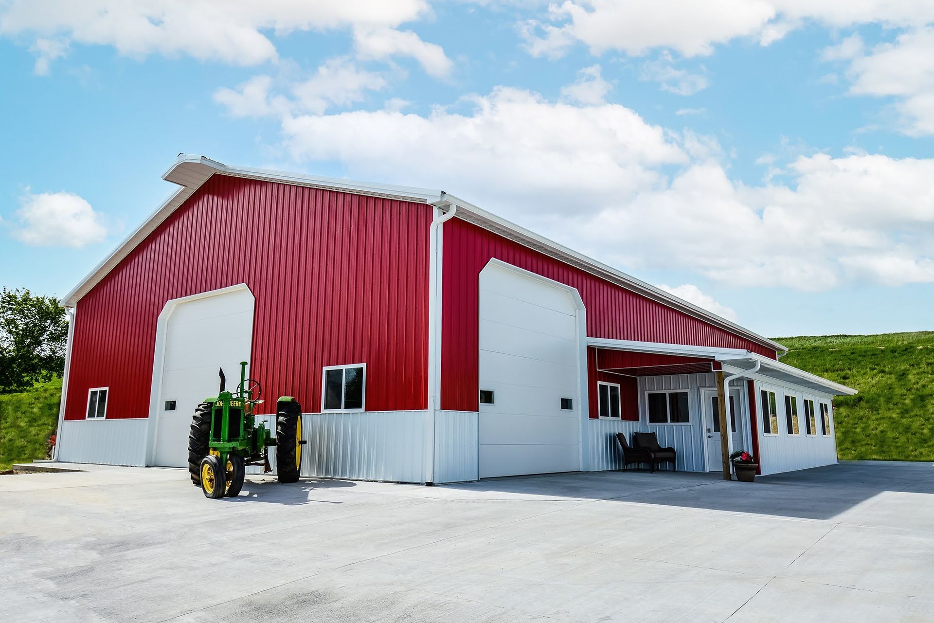 Dark gray metal agricultural building with white trim, large garage door, and small side door.