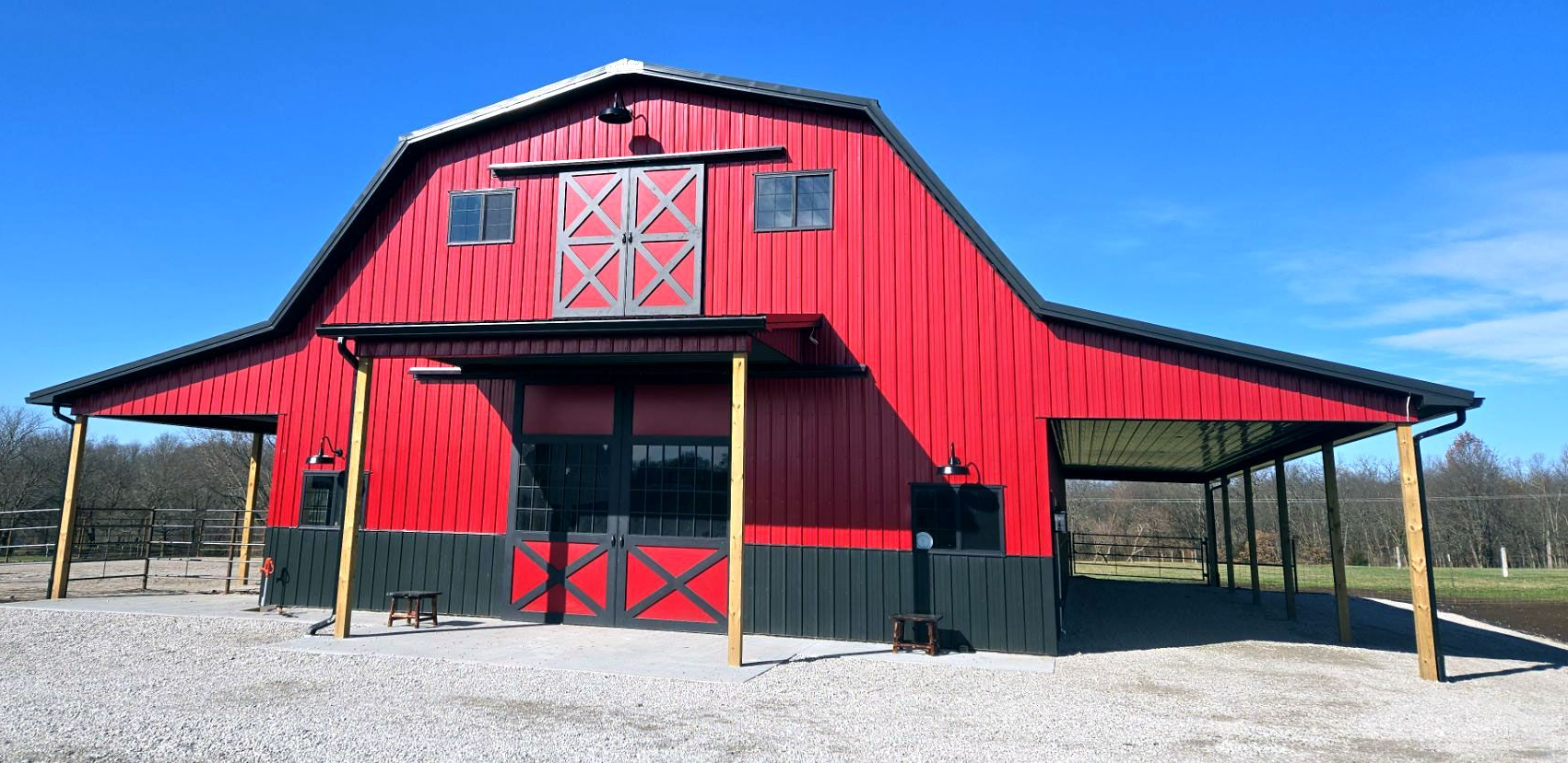 Red gambrel-roof barn with white trim and star accents, built by Gingerich Structures