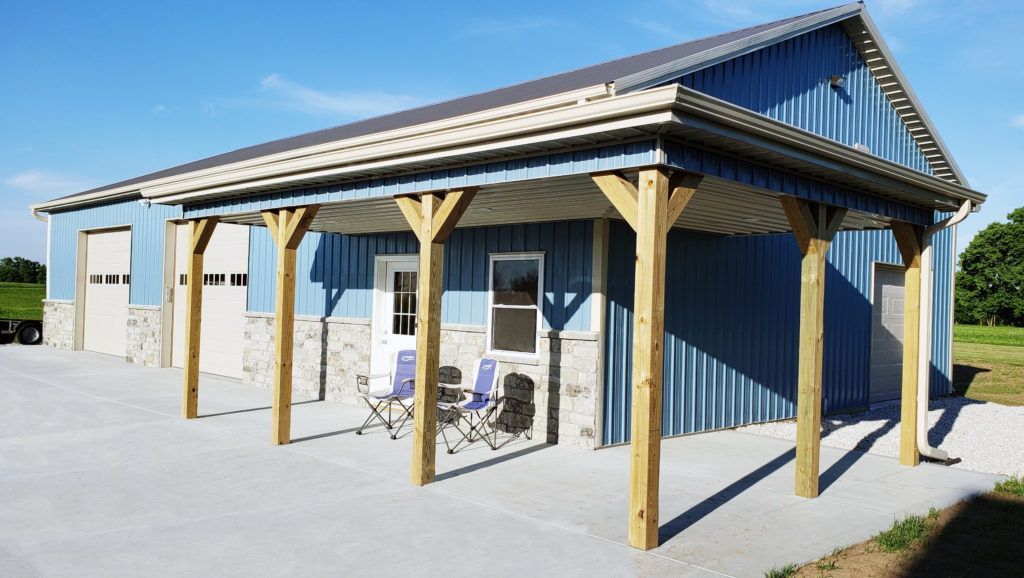 Blue metal building with a wooden porch and a concrete drive.