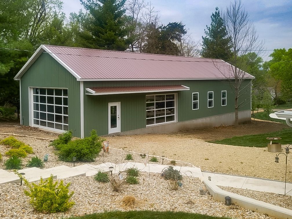 Dark gray metal agricultural building with white trim, large garage door, and small side door.
