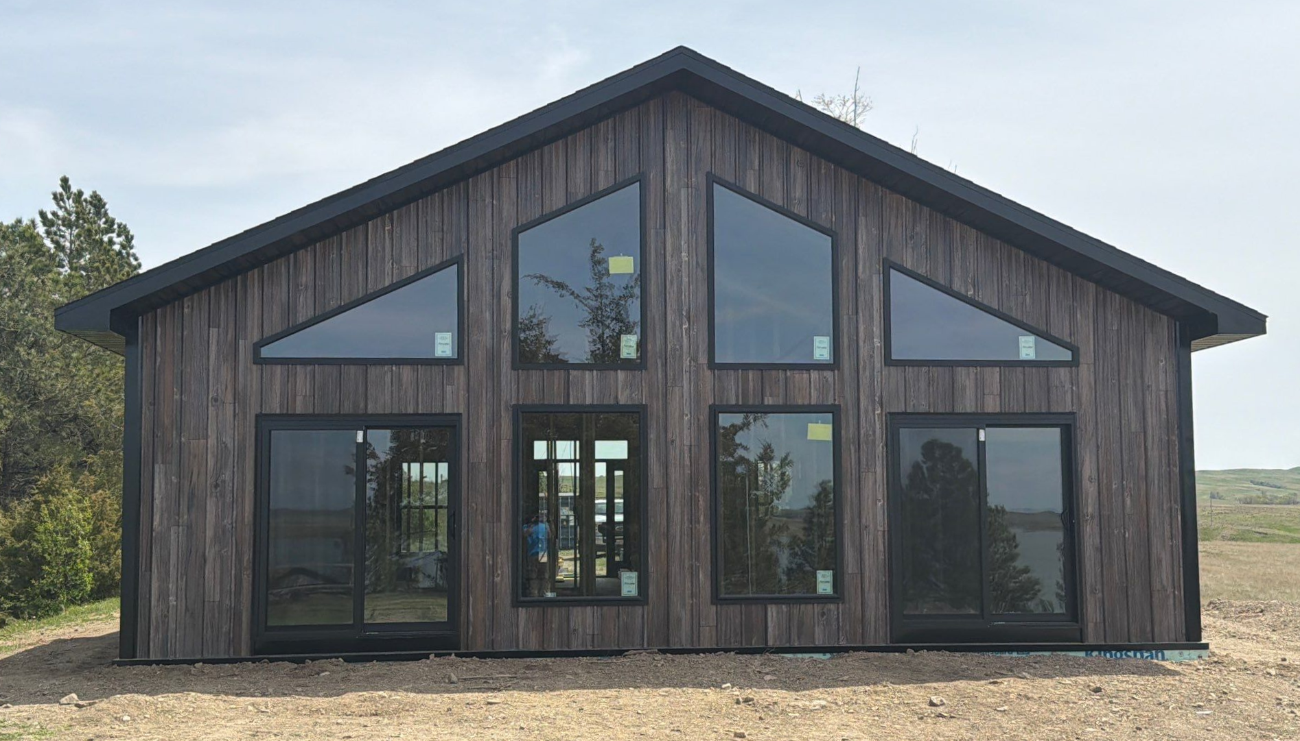 Modern post-frame barndominium with dark siding and floor-to-ceiling windows