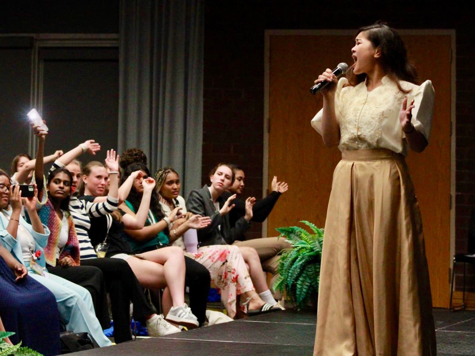 A woman is singing into a microphone in front of a crowd of people.