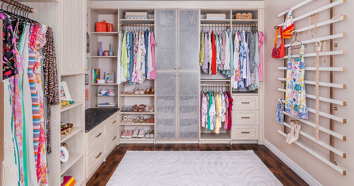 A well-organized walk-in closet with clothes, shoes, and a decorative wall rack.