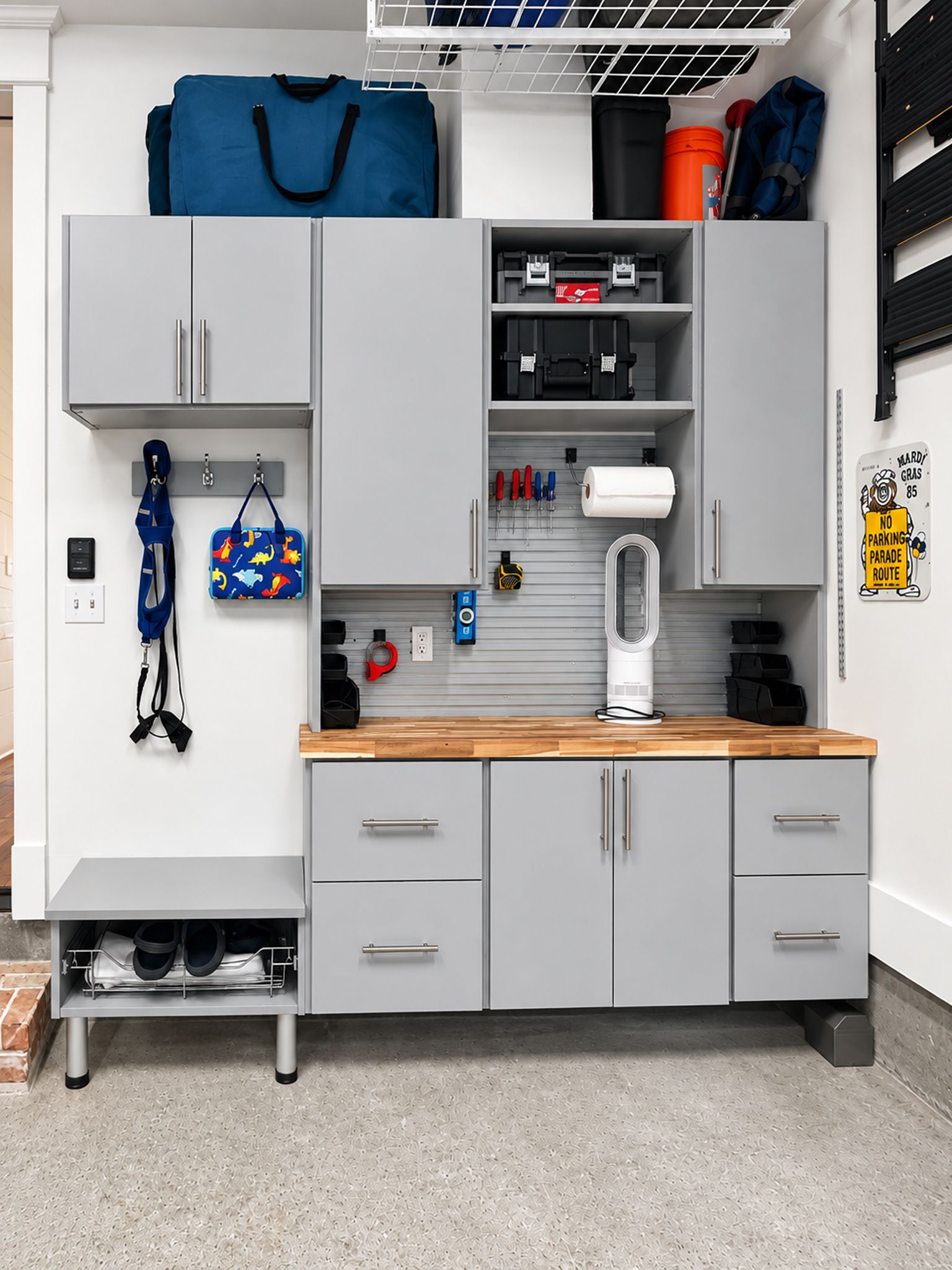 Garage storage cabinet with gray doors, wooden countertop, and organized tools and supplies