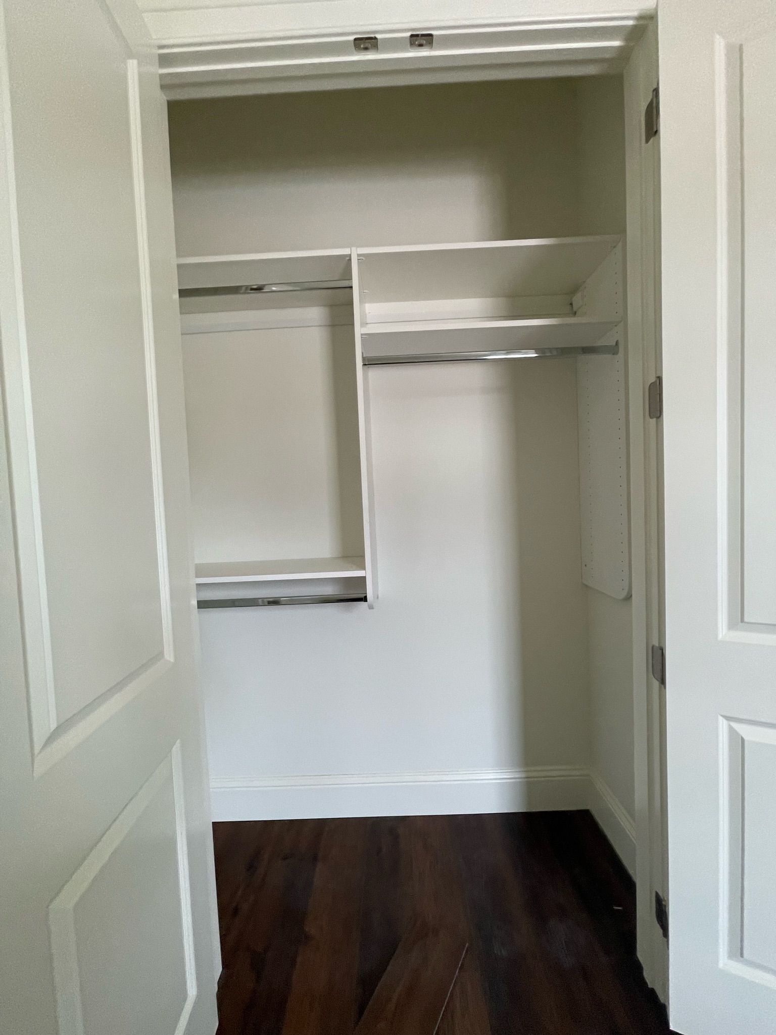 White closet with shelves and dark wood floor.