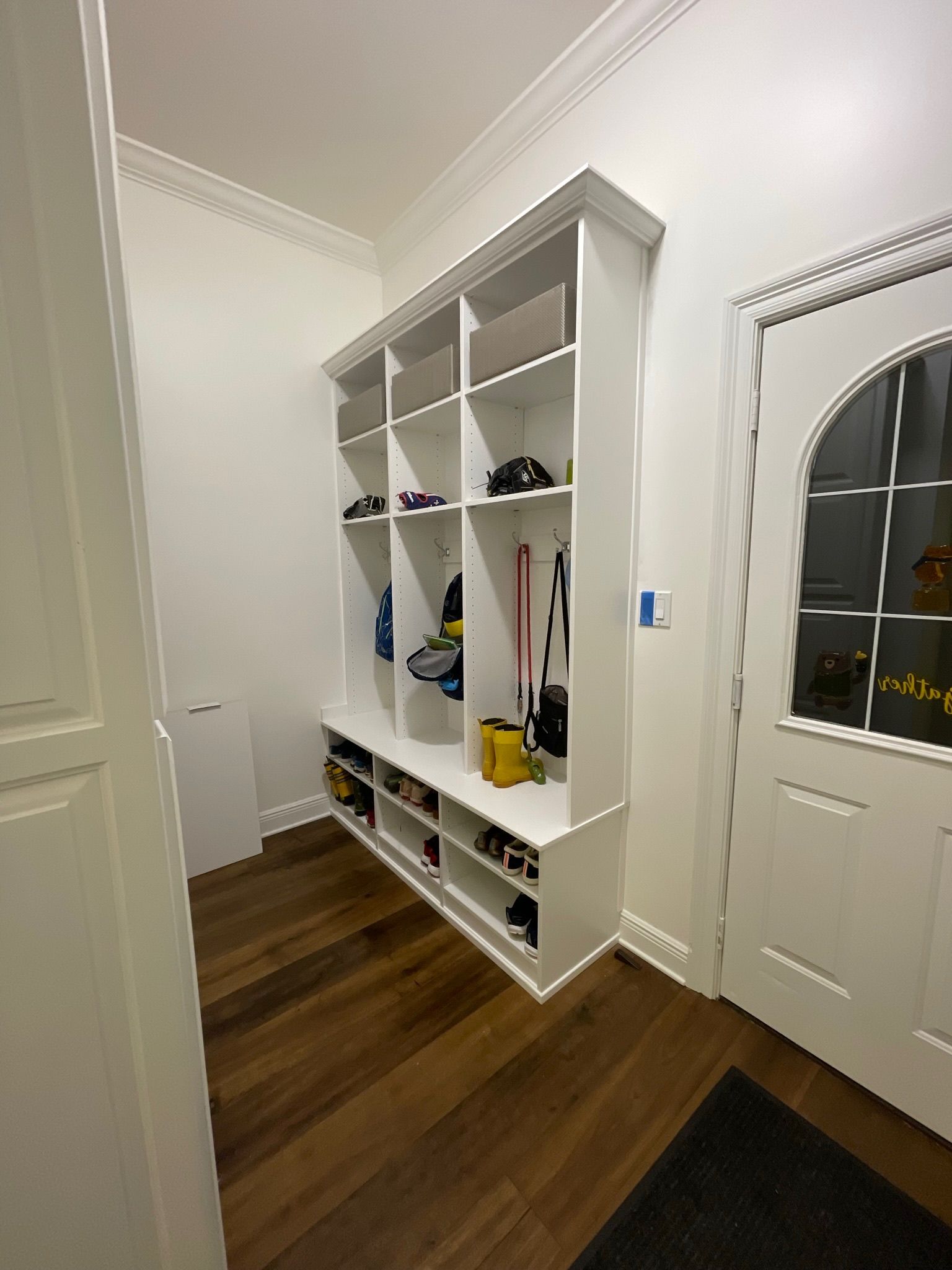 White entryway organizer with shelves and cubbies for storage, next to a white door.