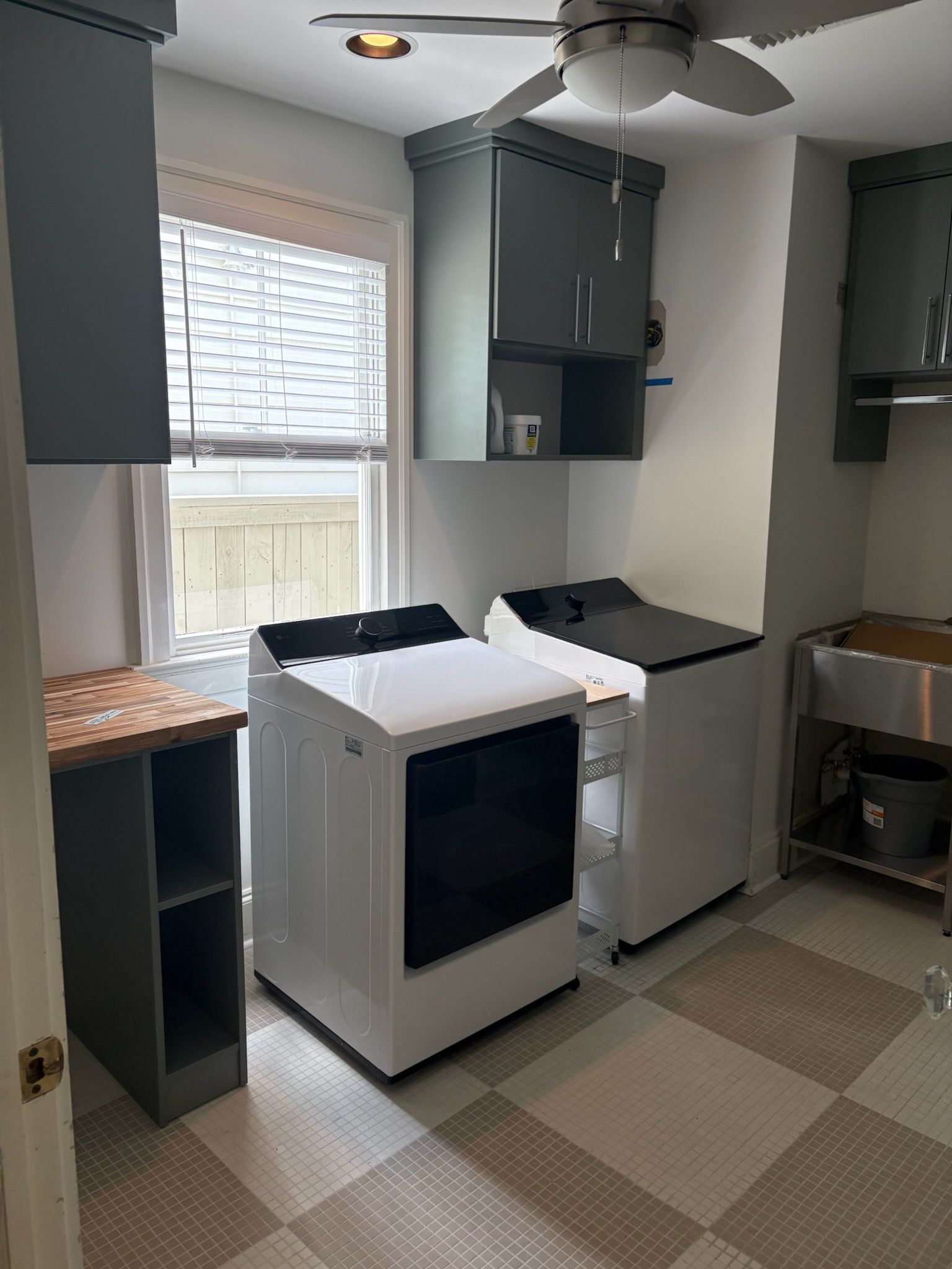 Laundry room with a washer, dryer, cabinets, and a sink.