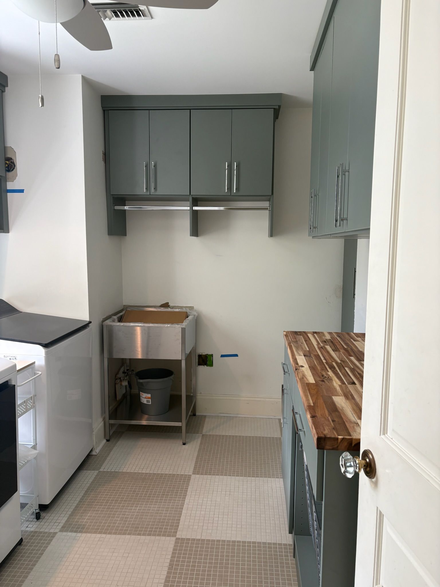 Laundry room with metal sink, gray cabinets, and checkered floor.