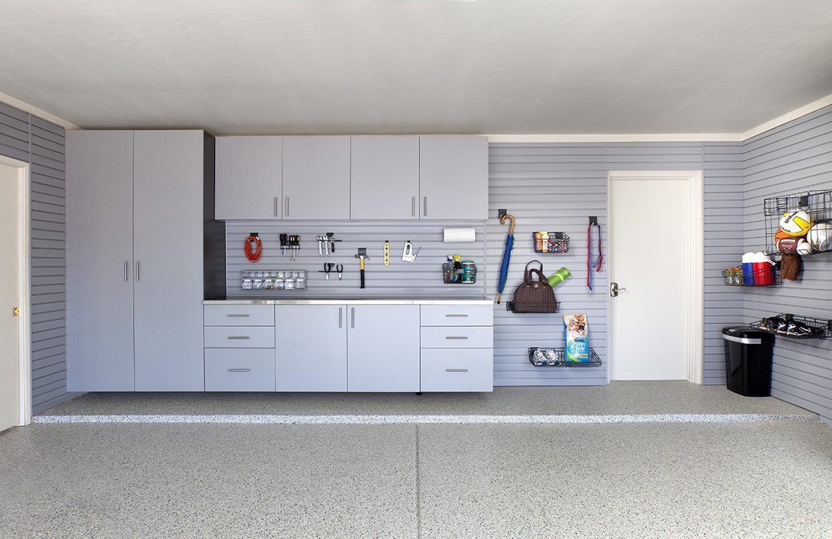 Garage interior with gray cabinets and pegboard storage on a speckled floor.