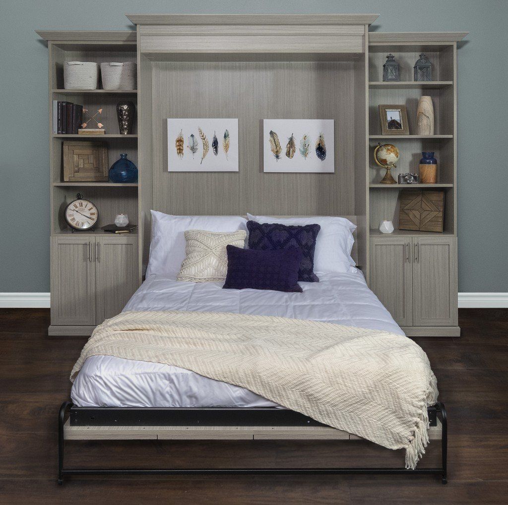 Gray wood wall bed with shelving and a bed frame, white bedding and decorative pillows, two paintings, home interior.