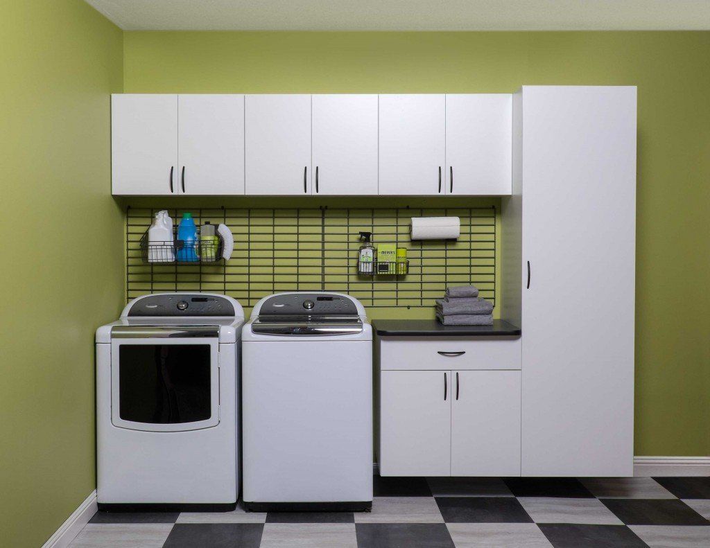 Laundry room with white appliances, cabinets, and olive green walls. Black and white checkered floor.