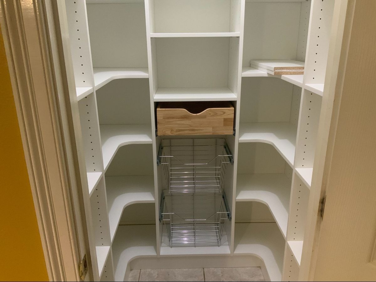 White pantry shelving with various compartments and a pull-out wire basket and wooden drawer.