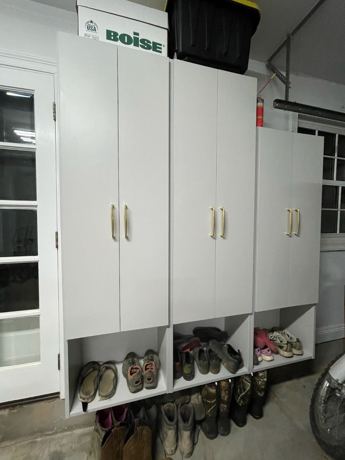 White storage cabinets with shoe storage in a garage.