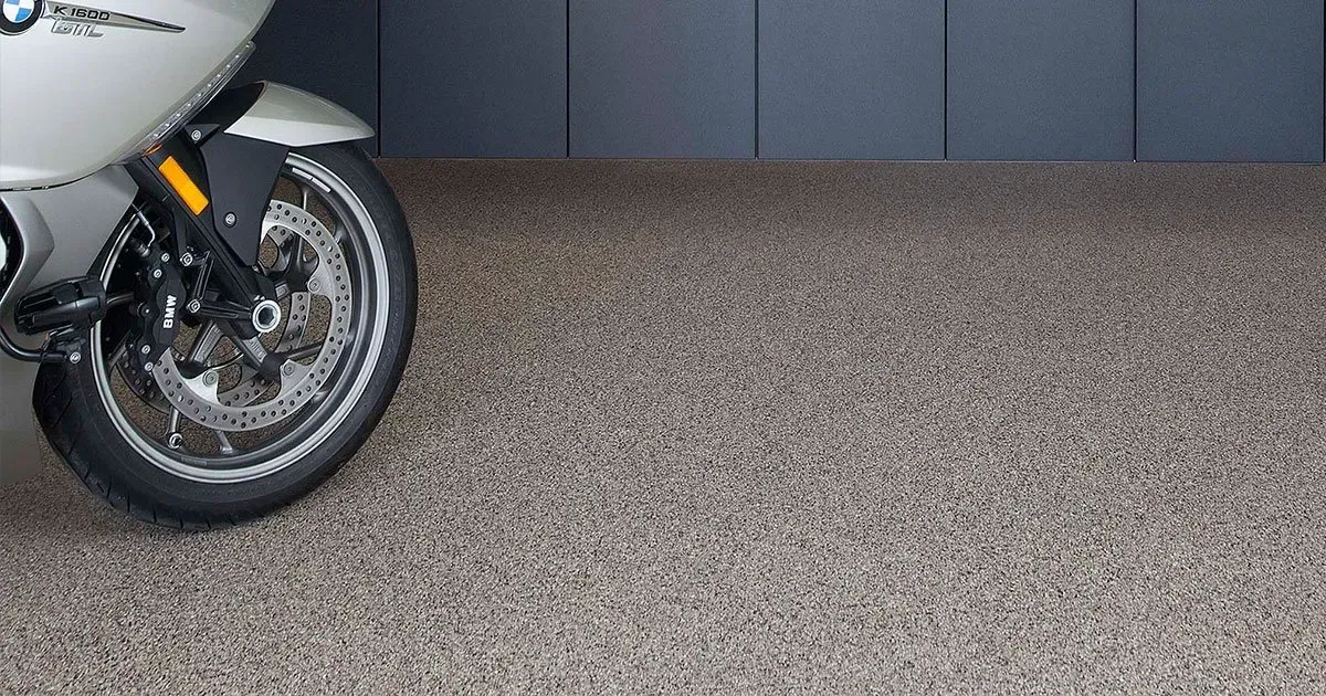 Motorcycle parked on a speckled floor in a garage with dark gray walls.
