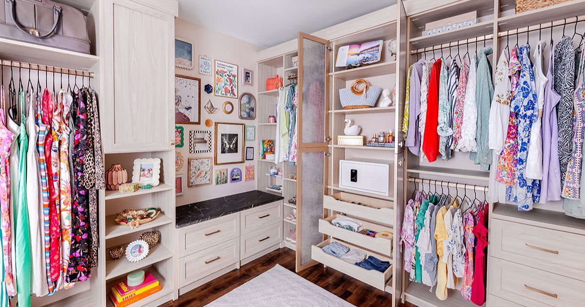 Dark gray walk-in closet with hanging clothes, drawers, shelves, and shoes, organized.