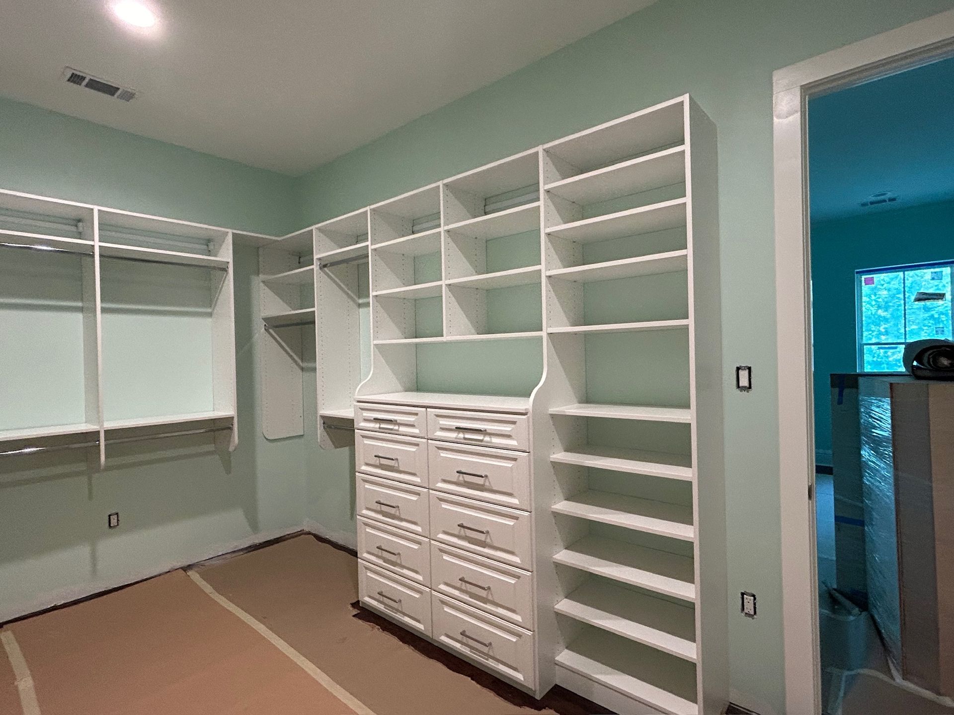 White custom closet shelving in a room with light green walls.