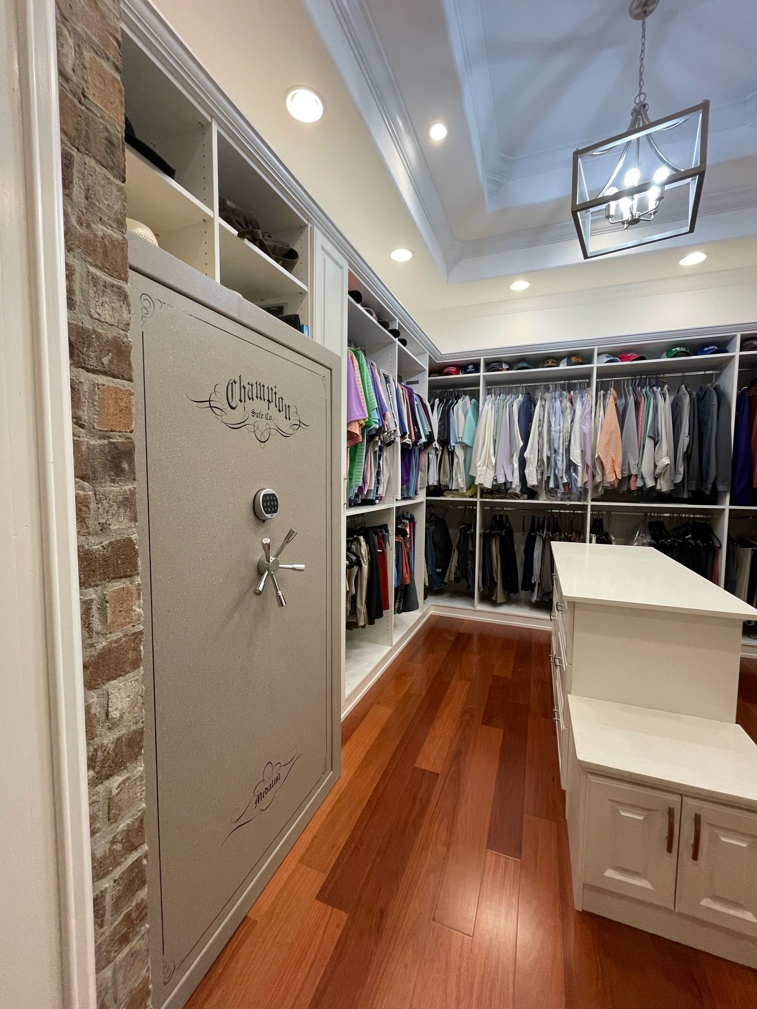 Walk-in closet with a safe, wood floor, and clothing racks.