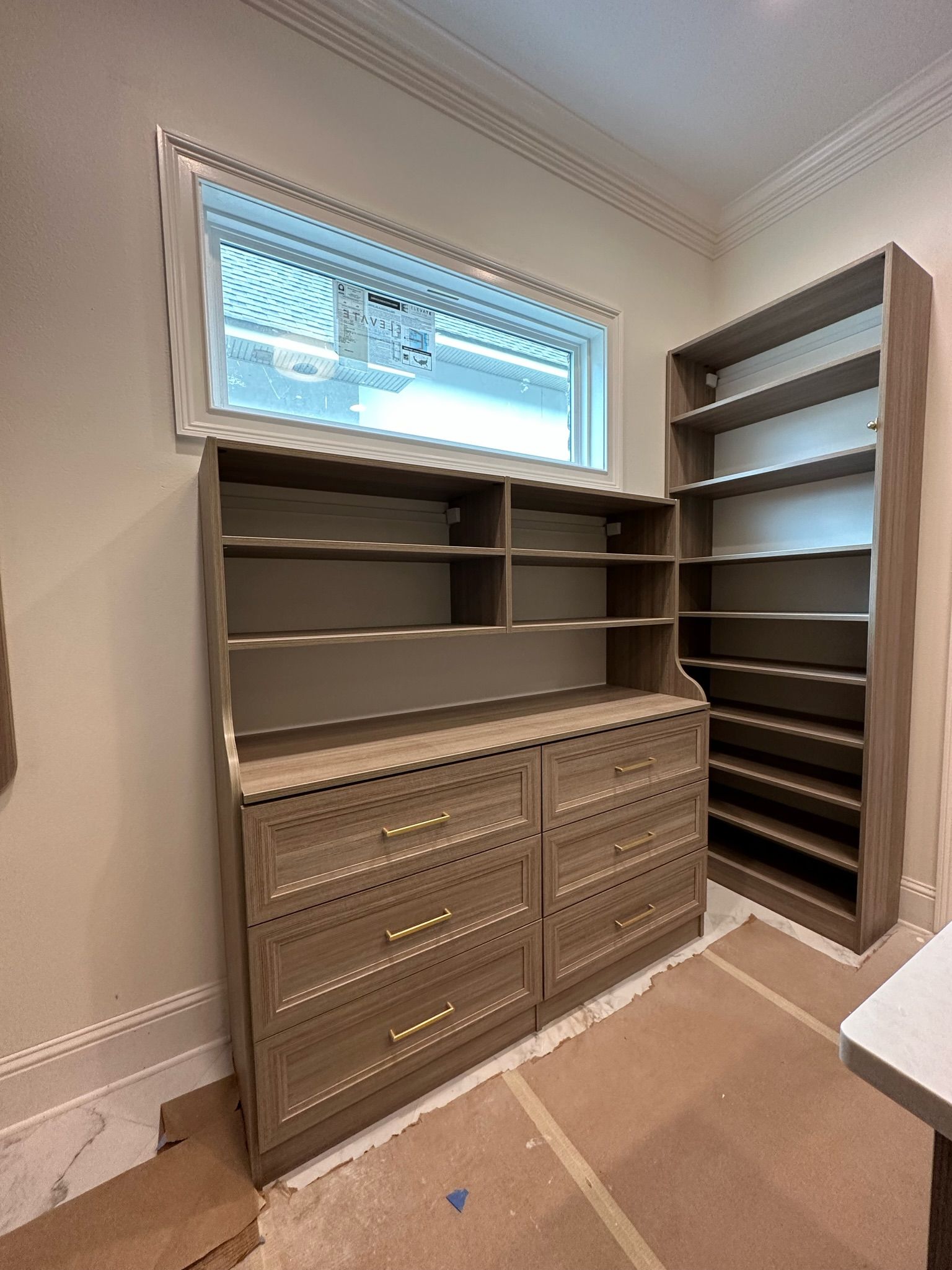 Wooden cabinetry and shelves installed in a room with a window.