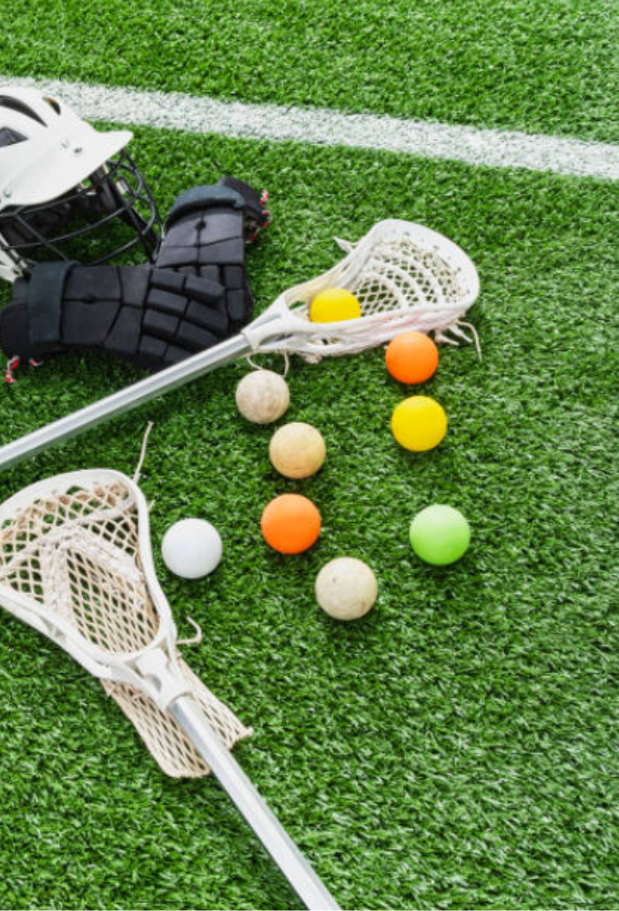 Lacrosse sticks, glove, and colorful balls on artificial turf field