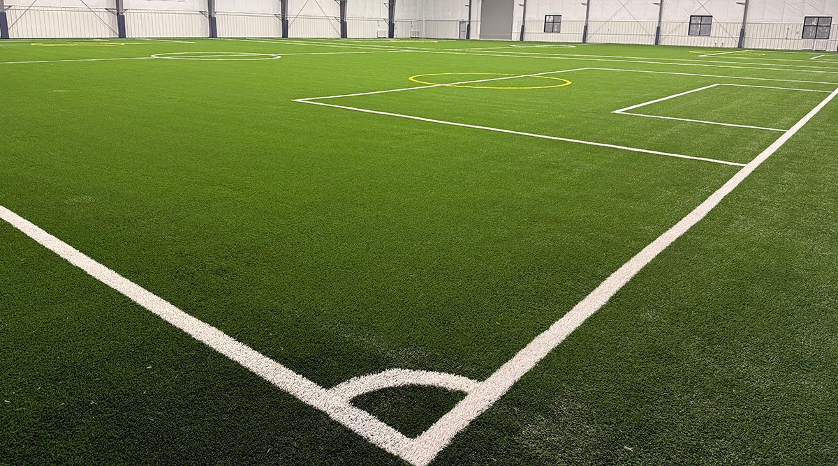 Indoor soccer field corner with bright green turf and white boundary lines