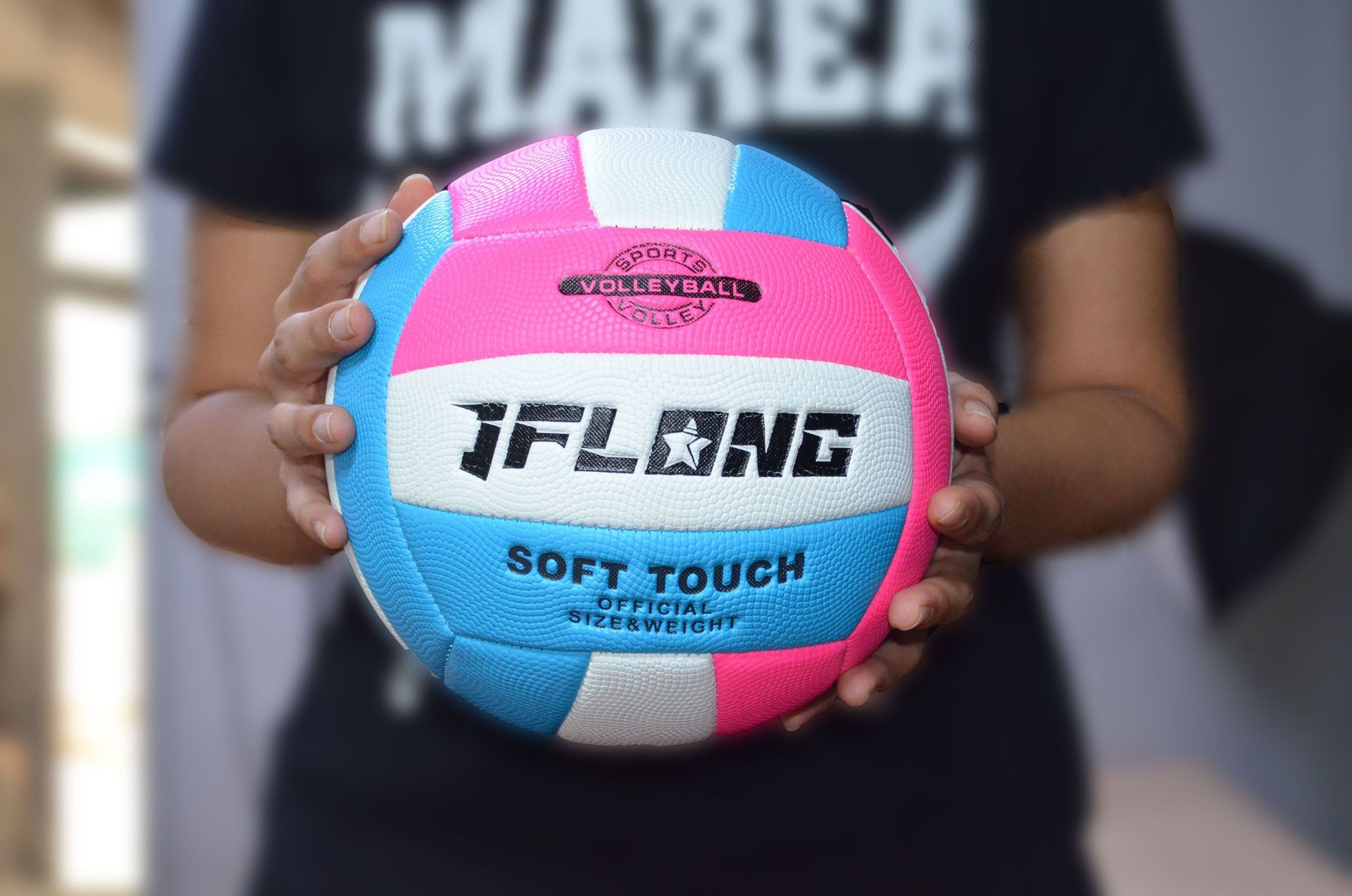 Hands holding a pink and blue volleyball with the word “JFLING” and “SOFT TOUCH” on it