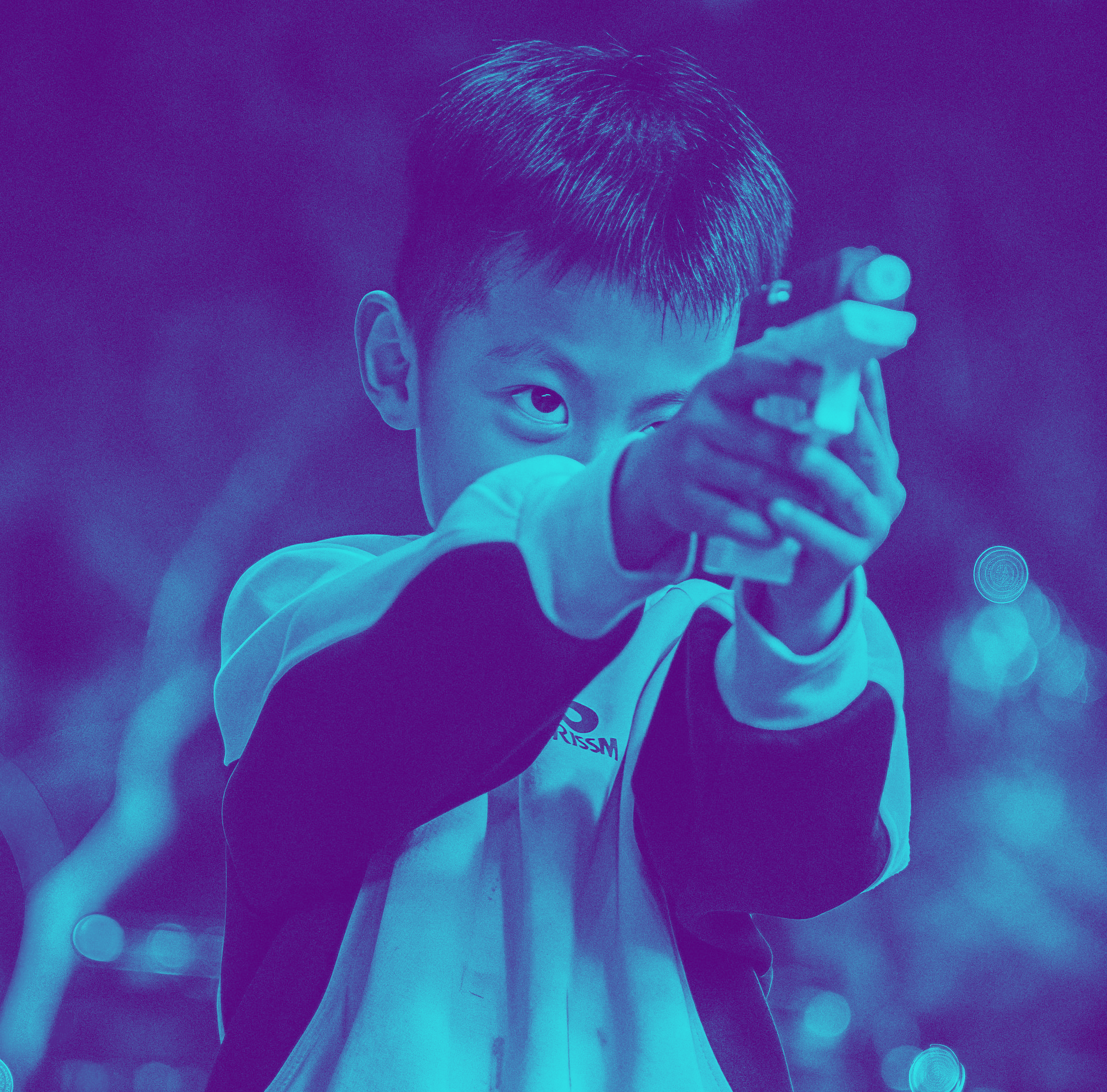 Child aiming a toy water gun, tinted blue and purple, in an outdoor setting