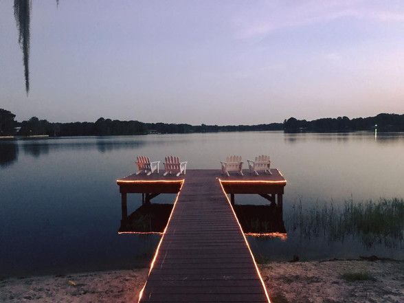 A dock with chairs on it is lit up at night