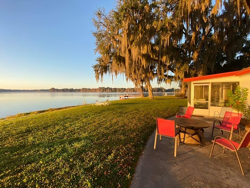 A patio with a table and chairs overlooking a lake - Sunshine Lodge