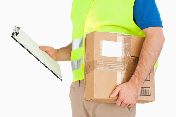 Delivery worker holding clipboard and cardboard box, wearing neon safety vest and blue shirt